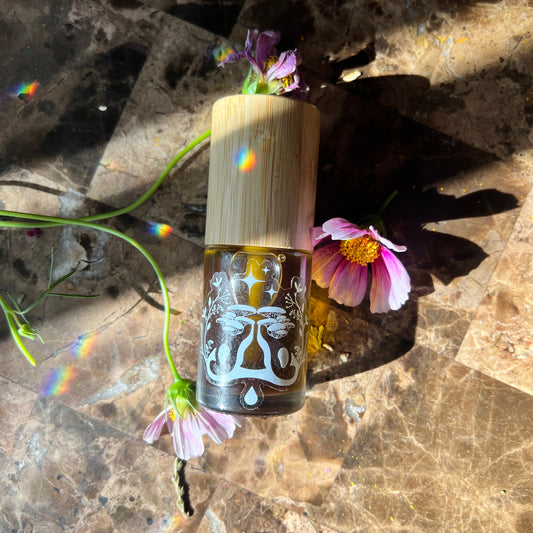 1oz glass bottle with bamboo cap on a stone surface with flowers | cannabliss body oil